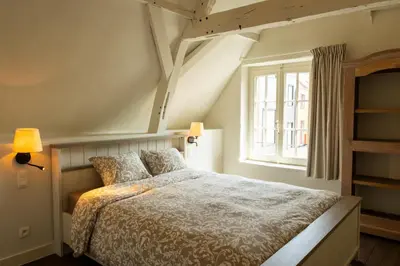 a bedroom with a bed and a window at Begijnhofpoort Vakantiehuis in Turnhout