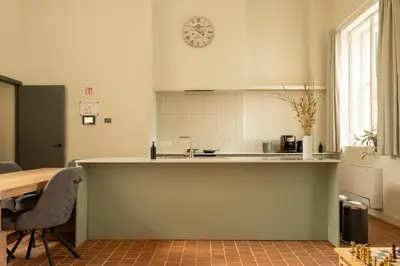 a kitchen with a table and a clock on the wall at Begijnhofpoort Vakantiehuis in Turnhout
