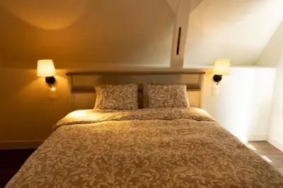 a bedroom with a large bed with two lamps at Begijnhofpoort Vakantiehuis in Turnhout