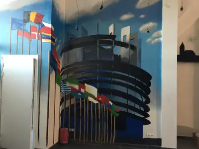 a mural of a building with flags on a wall at Midi 81 HOSTEL in Brussels