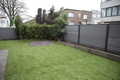 a backyard with a fence and a grass yard at Cozy family home near LottoArena Antwerpen in Antwerp