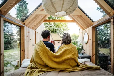 a couple sitting on a bed in a tiny house at Sterrenhuisje aan de Beddermolen in Westerlo