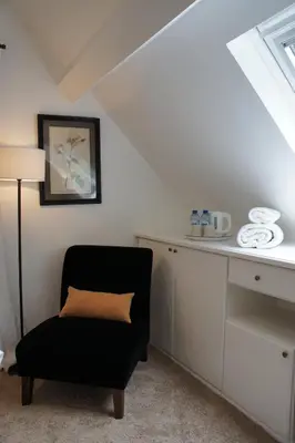 a room with a chair and a desk with a lamp at Guest house La Maison Chantecler in Brussels