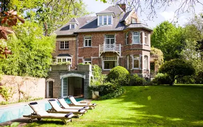 a large house with lounge chairs in the yard at Guest house La Maison Chantecler in Brussels