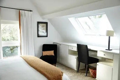 a bedroom with a bed and a desk and a window at Guest house La Maison Chantecler in Brussels