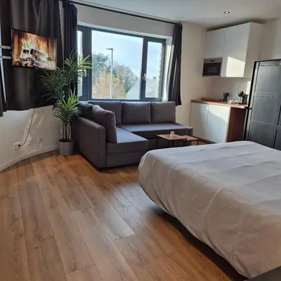 a bedroom with a bed and a couch and a kitchen at Orient Herent - Boetiekhotel in Herent