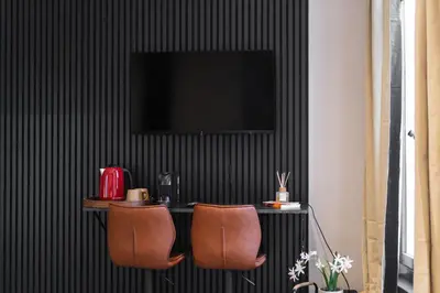 a table with two chairs and a television on a wall at 3 Stylish Studios at a Great Location in Gent in Ghent