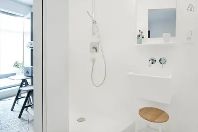 a white bathroom with a shower and a stool at B&B Lucy in the Sky in Antwerp