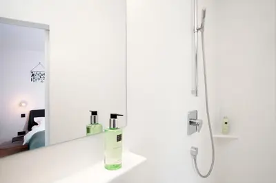 a white bathroom with a mirror and a shower at B&B Lucy in the Sky in Antwerp