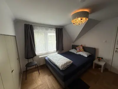 a bedroom with a blue bed and a chandelier at The Beautiful White House in Kortenberg