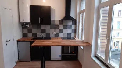 a kitchen with black cabinets and a counter top at Bel appartement proche de tout in Brussels