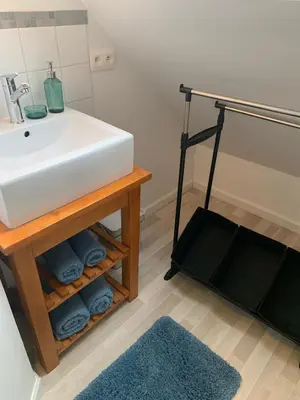 a bathroom with a sink and a shelf with towels at Sous un toit perché in Grez-Doiceau