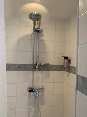 a shower with a hose in a bathroom at Sous un toit perché in Grez-Doiceau