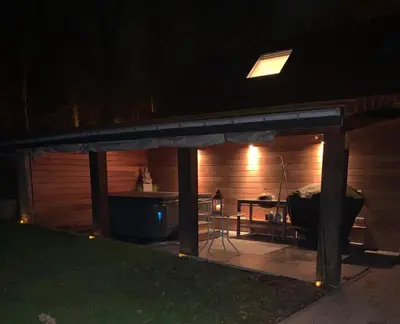 a screened in patio at night with a table at Sous un toit perché in Grez-Doiceau