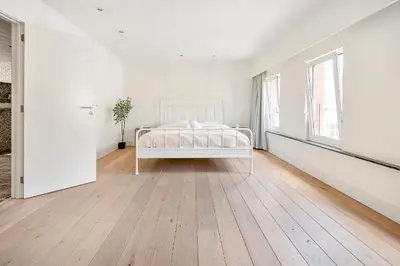a white bedroom with a bed and a window at Luxury apartment x big terrace in Sint-Niklaas