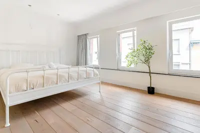 a white bedroom with a white bed and a wooden floor at Luxury apartment x big terrace in Sint-Niklaas