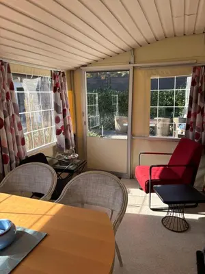 a living room with a red chair and tables and windows at Nomad Laryssiou on camping GT Keiheuvel parcel 371 in Balen