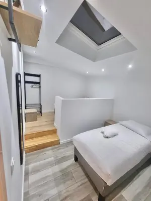 a white bedroom with a bed and a staircase at Plantin 4 in Brussels