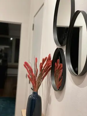a blue vase with red flowers in it next to mirrors at The Green Gatsby in Antwerp