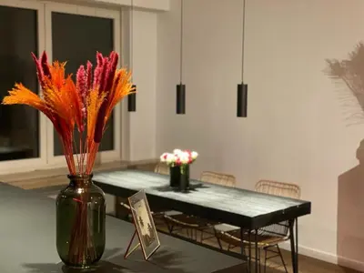 a dining room with a table and a vase with flowers at The Green Gatsby in Antwerp