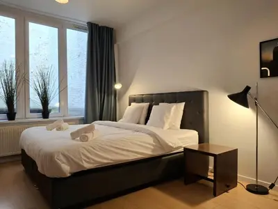 a bedroom with a large bed with white sheets and a table at Spacious next to Grand Place in Brussels