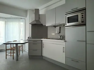 a white kitchen with a table and a microwave at Central in the heart of Brussels in Brussels