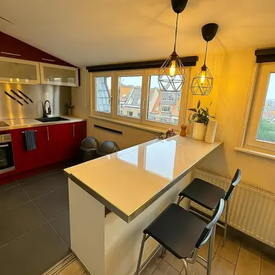 a kitchen with red cabinets and a counter with chairs at Brussels Quiet Oasis in Brussels