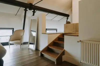 a staircase in a room with a mirror and chairs at Magnificent loft - 3 bedroom duplex in Brussels