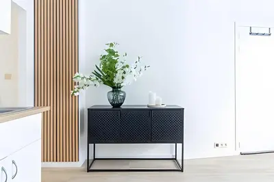 a black side table with a vase of flowers on it at Studio calme et fonctionnel – idéal séjour pro in Brussels
