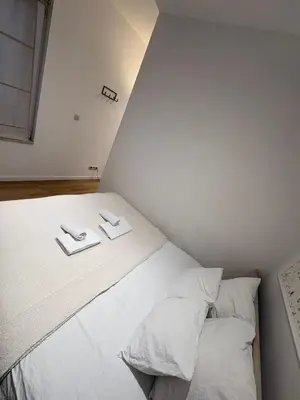 a bed with white sheets and pillows in a room at Charming studio, perfect getaway in Brussels