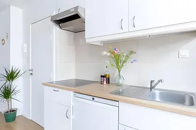 a white kitchen with white cabinets and a sink at Studio lumineux, idéal pour séjour pro in Brussels