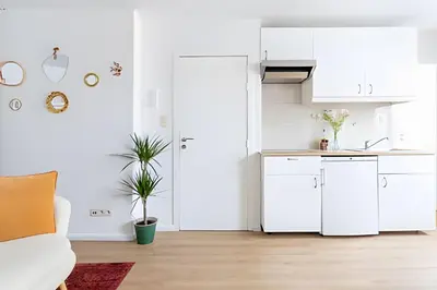 a kitchen with white cabinets and a white couch at Studio lumineux, idéal pour séjour pro in Brussels