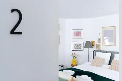 a white bedroom with two beds and a number two at Studio lumineux, idéal pour séjour pro in Brussels