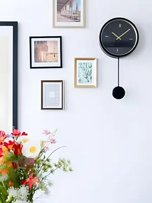 a clock on a wall with pictures and a vase of flowers at Studio lumineux, idéal pour séjour pro in Brussels