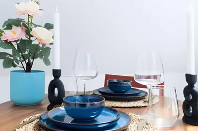 a dining room table with blue dishes and wine glasses at Appartement cosy et central – séjour pro in Brussels