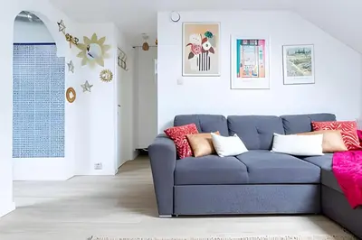 a living room with a blue couch with red pillows at Appartement cosy et central – séjour pro in Brussels