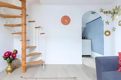 a living room with a spiral staircase and a blue couch at Appartement cosy et central – séjour pro in Brussels