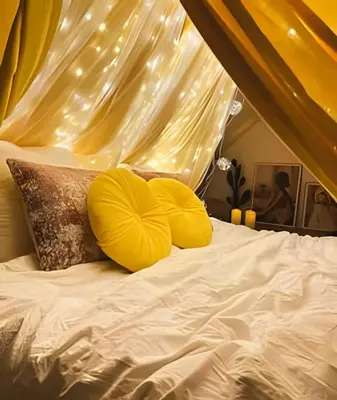a bed with yellow pillows and a canopy with lights at Appartement cosy et central – séjour pro in Brussels