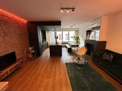 a living room with a green couch and a brick wall at The Green Gatsby II in Antwerp