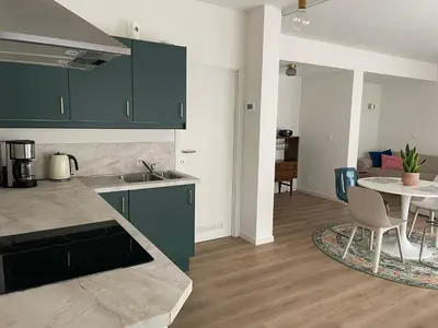 a kitchen with green cabinets and a table and a dining room at Bright apartment with private parking near Ghent city centre in Ghent