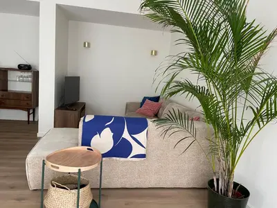 a living room with a couch and a palm tree at Bright apartment with private parking near Ghent city centre in Ghent