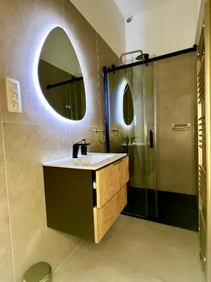 a bathroom with a sink and a shower with a mirror at Luxury Suites Royal by Rikas Hotels in Antwerp