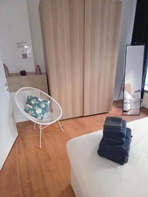 a room with a bed and a chair and a mirror at Lovely & Modern apartment in the heart of Antwerp in Antwerp