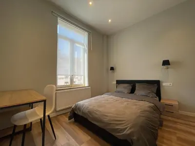 a bedroom with a bed and a desk and a window at Midi Station in Brussels