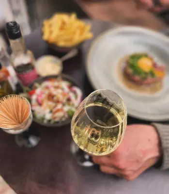 a glass of wine sitting on a table with food at The Cozy Guestroom near Park Zuid and Musea in Antwerp