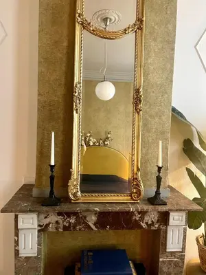 an ornate gold mirror on a table with two candles at The Cozy Guestroom near Park Zuid and Musea in Antwerp