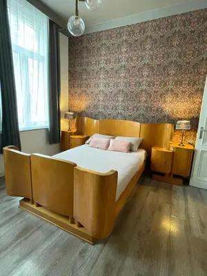 a bedroom with a large wooden bed with two pink pillows at The Art Deco Guestroom near Musea in Antwerp