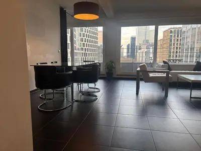 a room with a table and chairs and a large window at Charming central apartments with balcony views in Brussels