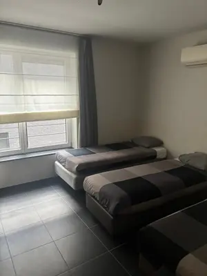 two beds in a room with a window at Charming central apartments with balcony views in Brussels