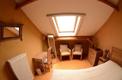 a attic room with a window and a table and chairs at Huis van Rooi in Sint-Agatha-Rode